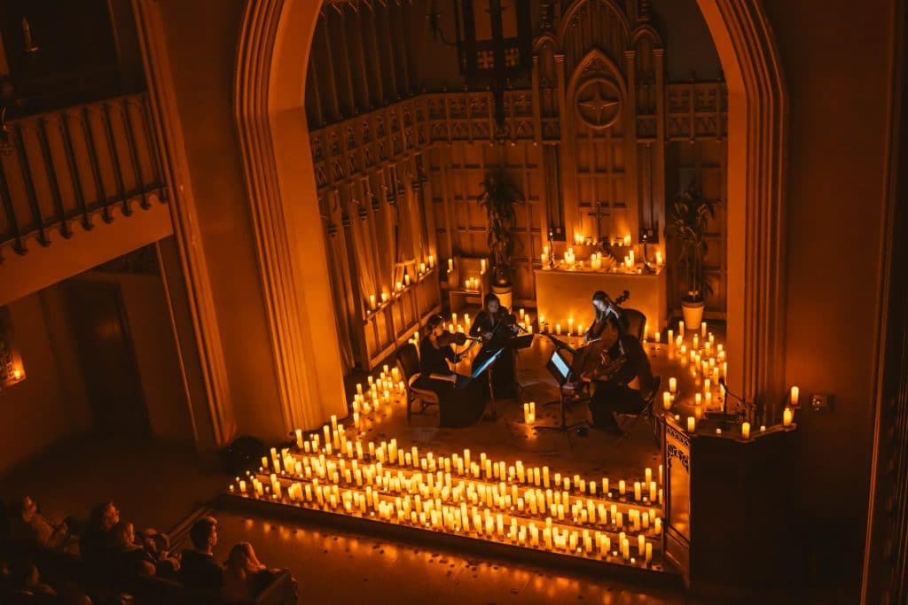 musicians surrounded by candles in what looks like a cathedral at a Candlelight concert.