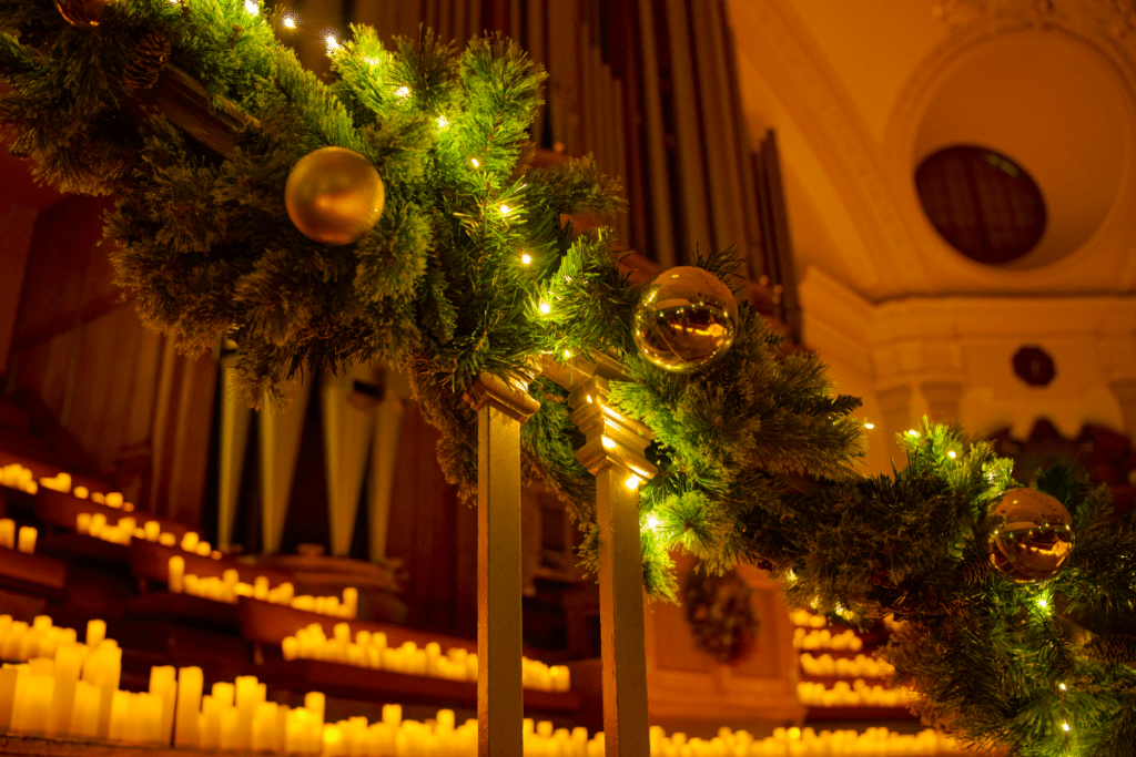 A staircase adorned with a wreath, baubles and candles