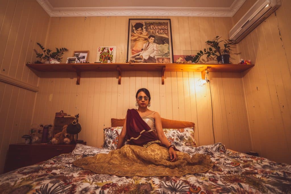 a photo of a woman sitting in bed with sunglasses on