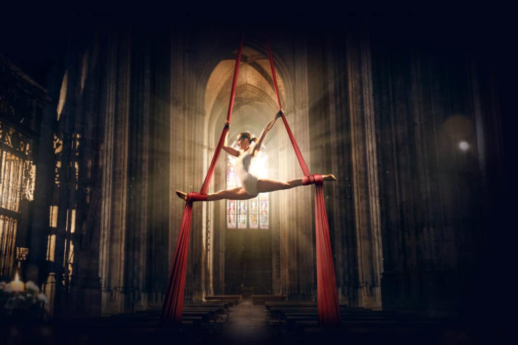 a photo of a woman doing a circus act inside a cathedral