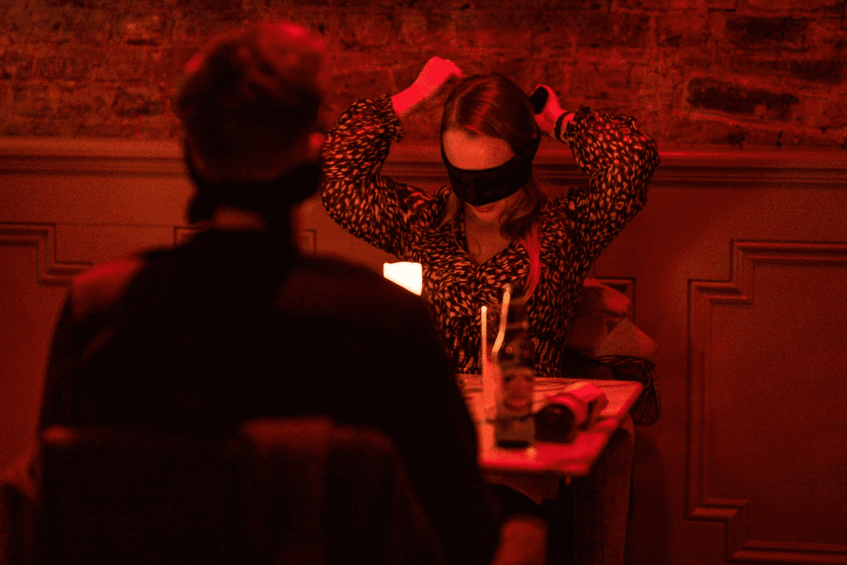 A woman placing a blindfold over her eyes at the Dining in the Dark experience.
