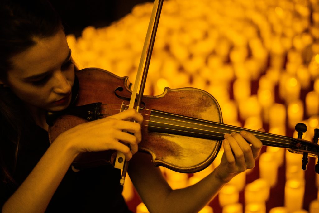 close up of violinist performing Candlelight concert in front of hundreds of candles