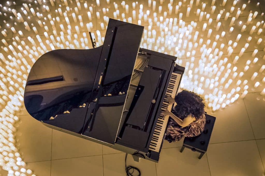 bird view of a pianist performing while surrounded by hundreds of candles