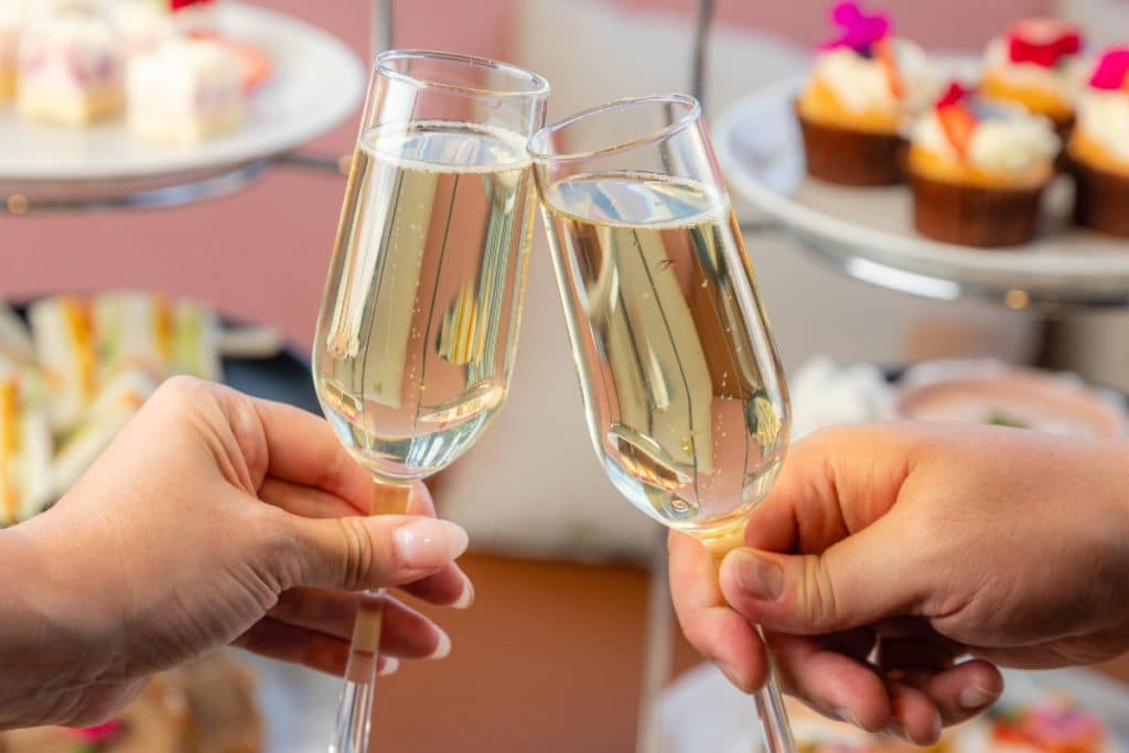 an upclose photo of two champagne glasses cheersing