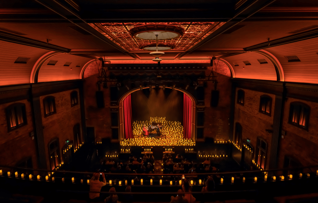 candlelight concert at the princess theatre in brisbane with pianist and other string musician on stage surrounded by candles