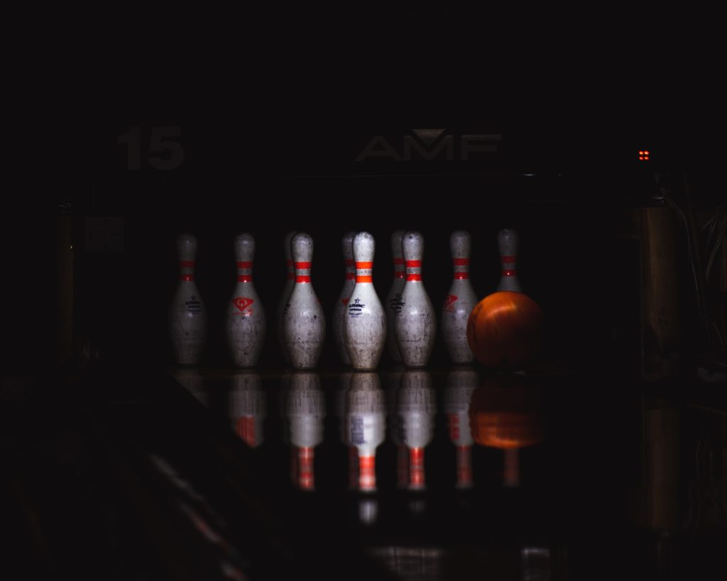 Seven bowling pins set up on the bowling lane. Everything around the pins is dark.