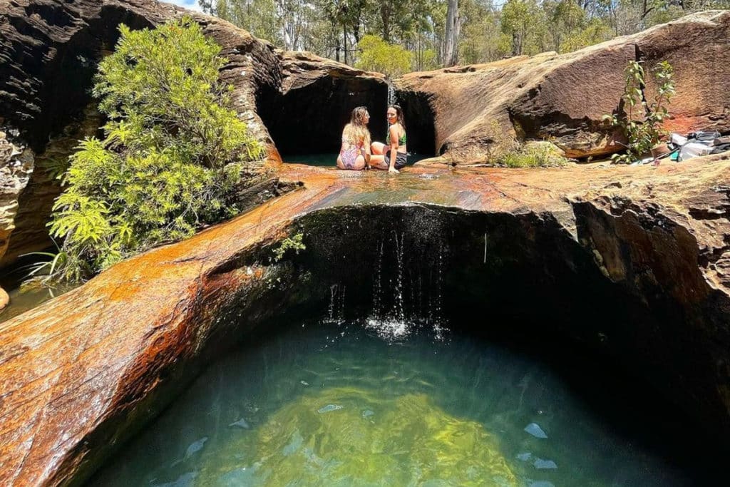two girls sitting by a rock pool in the central queensland highlands