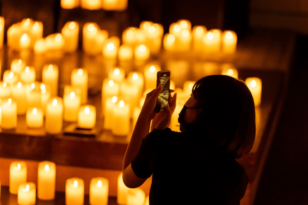 Woman taking a photo on her phone at a candlelight concert