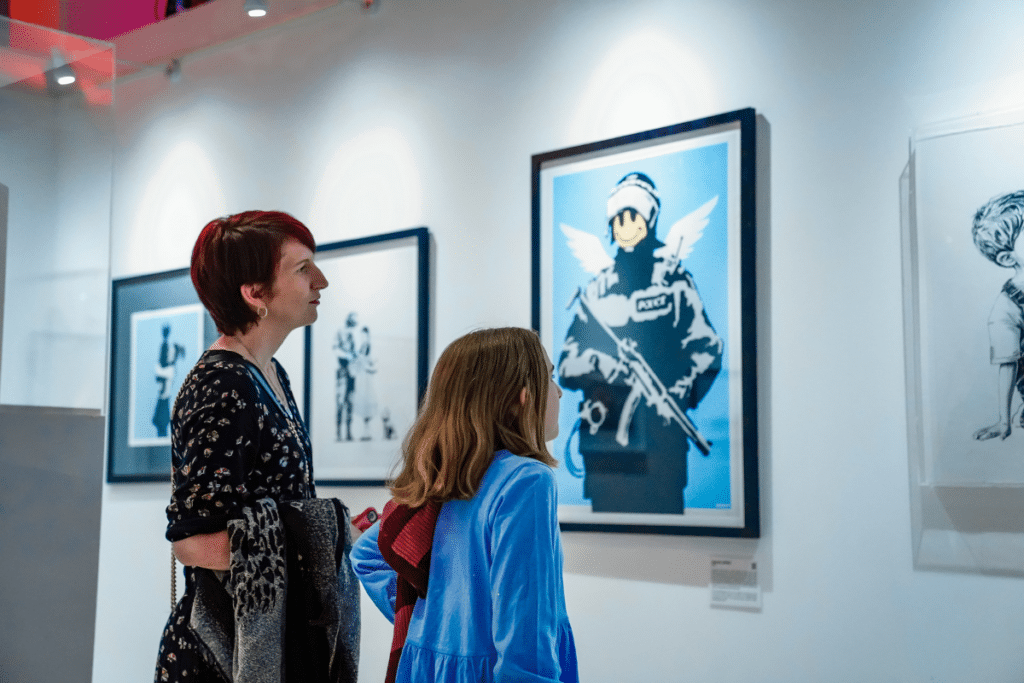 Young girl and older woman looking at an artwork at the Banksy Exhibition in Brisbane