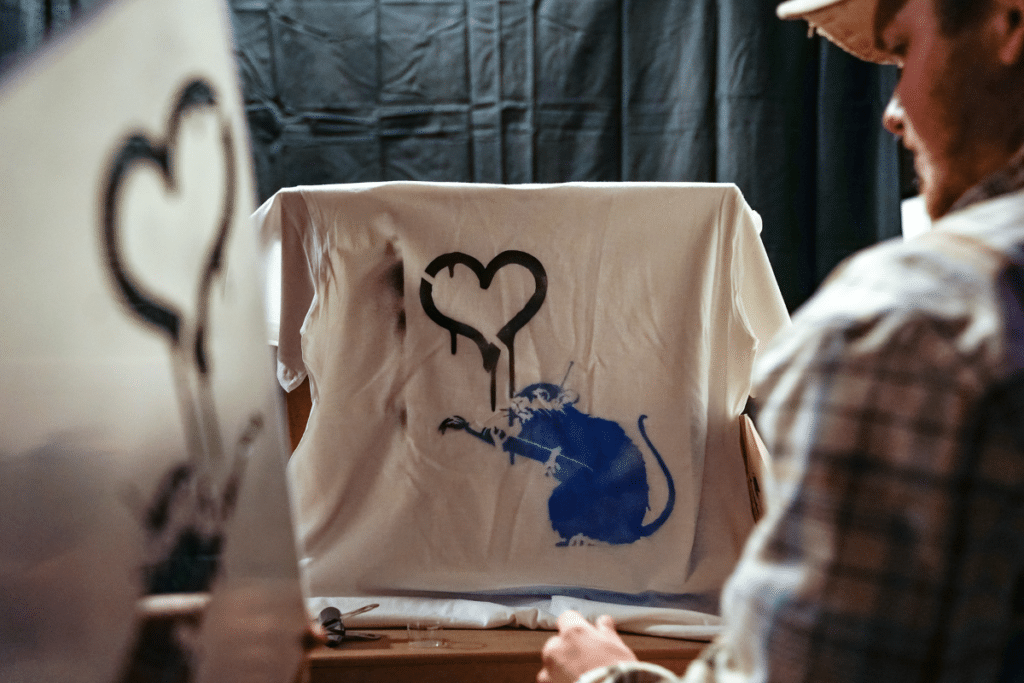Man spray painting a t-shirt at the Banksy Exhibition in Brisbane