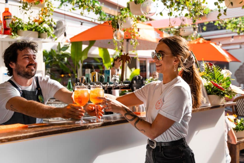 a photo of a bartender holding aperol spritzes