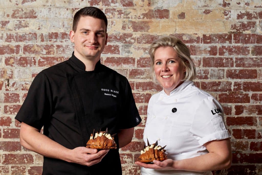 a photo of a man and woman standing side by side holding a croissant each