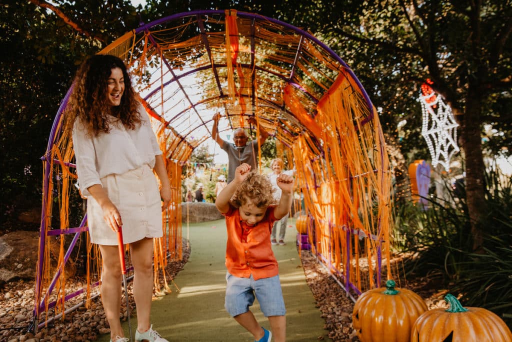 a photo of a kid and mother at halloween-themed putt putt